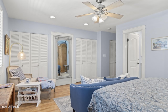 bedroom featuring ceiling fan, multiple closets, and light wood-type flooring