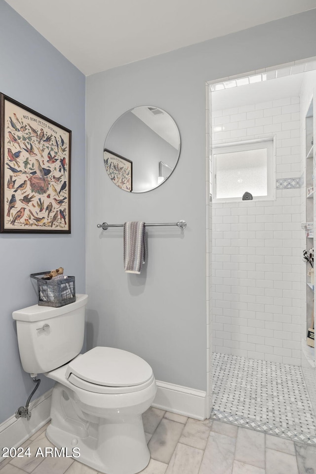 bathroom featuring toilet, tile flooring, and a tile shower