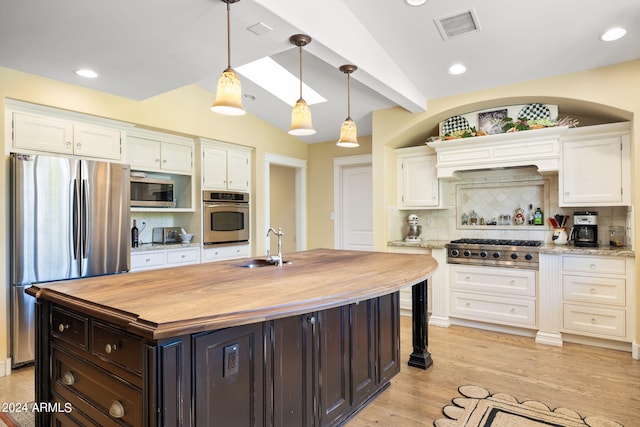 kitchen with vaulted ceiling with beams, appliances with stainless steel finishes, tasteful backsplash, and a kitchen island with sink