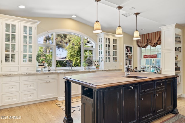 kitchen with hanging light fixtures, light hardwood / wood-style flooring, vaulted ceiling, and butcher block counters