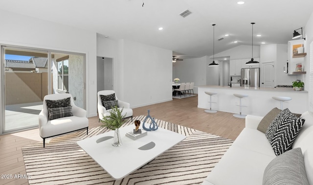 living room featuring vaulted ceiling, sink, and light hardwood / wood-style flooring