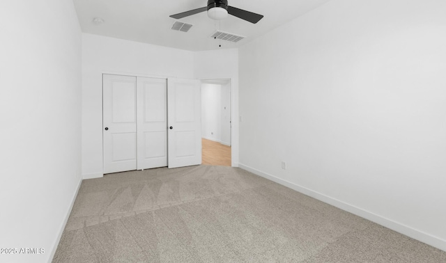 unfurnished bedroom featuring ceiling fan, a closet, and light carpet