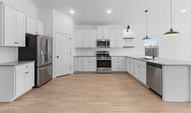 kitchen with appliances with stainless steel finishes, decorative light fixtures, sink, white cabinets, and kitchen peninsula