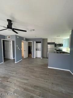 unfurnished living room featuring dark wood-type flooring and ceiling fan