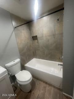 bathroom with toilet, tiled shower / bath, and hardwood / wood-style flooring