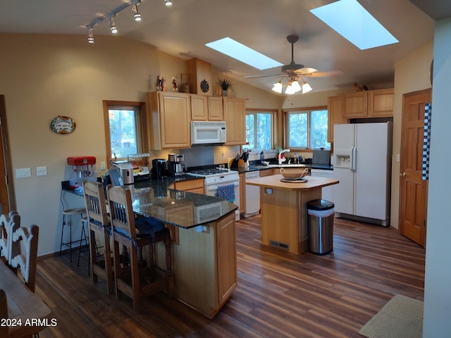 kitchen with lofted ceiling with skylight, a center island, dark wood-type flooring, and white appliances