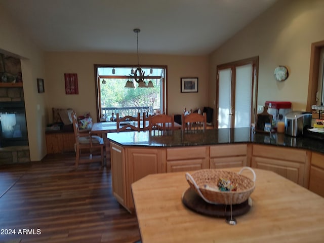 kitchen featuring lofted ceiling, decorative light fixtures, light brown cabinetry, a chandelier, and dark hardwood / wood-style flooring