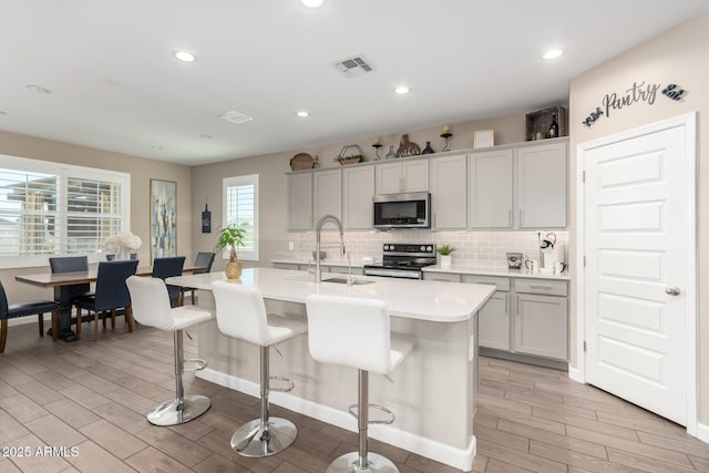 1297 W Chillingham Rd W, San Tan Valley, AZ 85143 - kitchen with appliances with stainless steel finishes, light wood-type flooring, light countertops, a sink, and a breakfast bar area