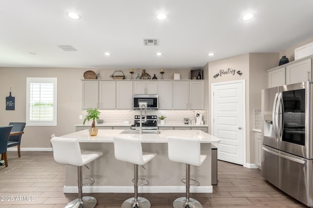 1297 W Chillingham Rd W, San Tan Valley, AZ 85143 - kitchen featuring appliances with stainless steel finishes, tasteful backsplash, light countertops, light wood-type flooring, and baseboards