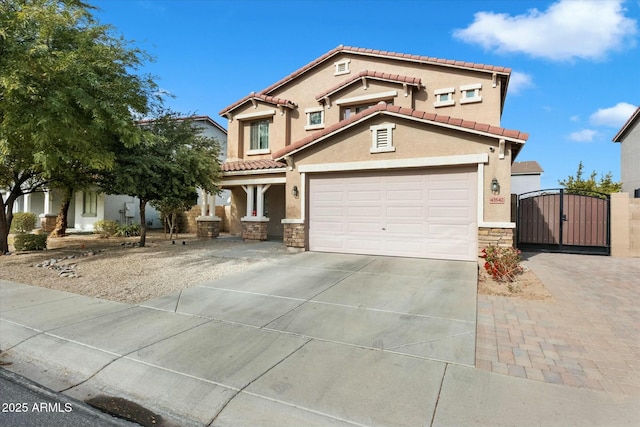 mediterranean / spanish home featuring concrete driveway, a tiled roof, stone siding, a gate, and stucco siding