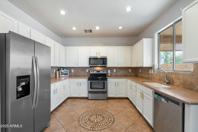 kitchen with stainless steel appliances, a sink, visible vents, white cabinets, and decorative backsplash