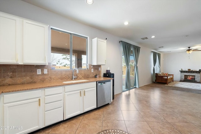 kitchen with light countertops, stainless steel dishwasher, open floor plan, white cabinetry, and a sink