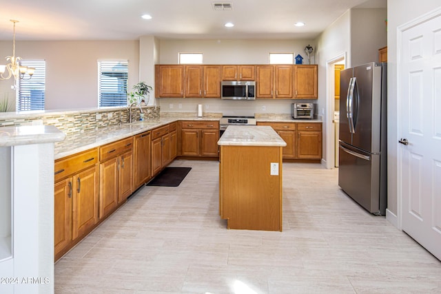 kitchen featuring pendant lighting, sink, a notable chandelier, a kitchen island, and stainless steel appliances