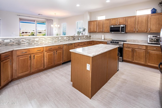 kitchen with sink, hanging light fixtures, an inviting chandelier, a kitchen island, and appliances with stainless steel finishes