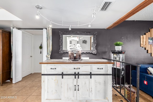 interior space featuring track lighting, light tile patterned floors, and white cabinets