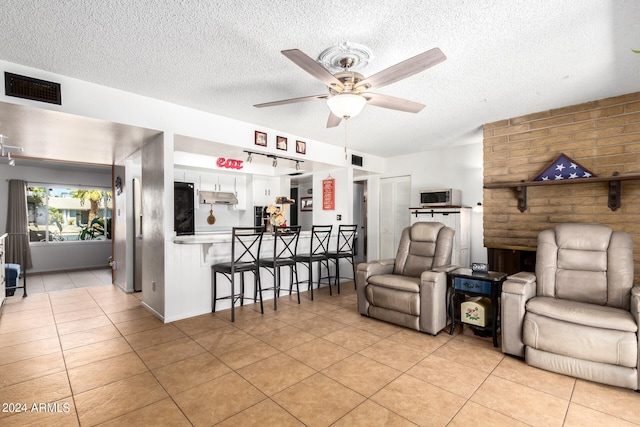 tiled living room with ceiling fan and a textured ceiling