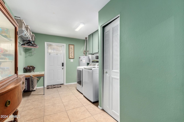 laundry area with washing machine and dryer, water heater, light tile patterned flooring, and cabinets