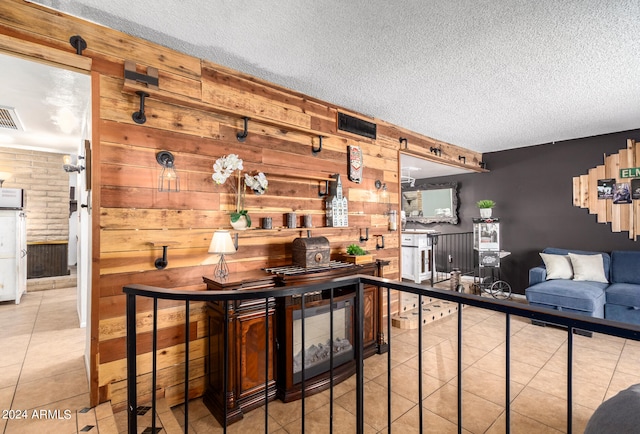 interior space with light tile patterned floors, wooden walls, and a textured ceiling