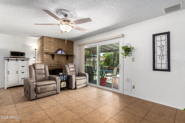 tiled living room featuring ceiling fan and a textured ceiling