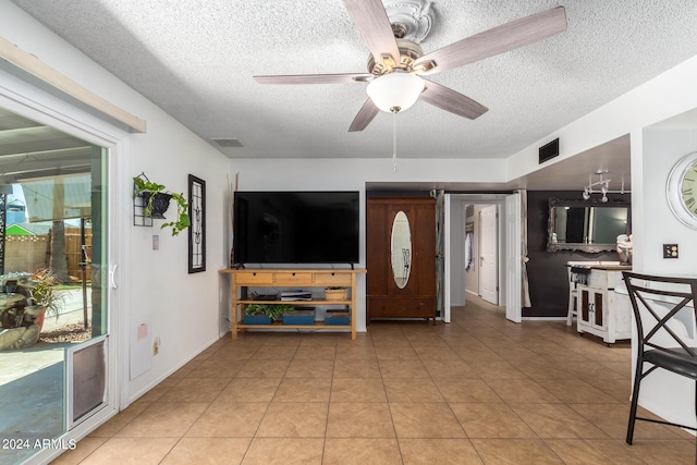 living room with ceiling fan, tile patterned flooring, and a textured ceiling