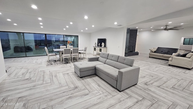 living room featuring a fireplace, light parquet floors, and ceiling fan