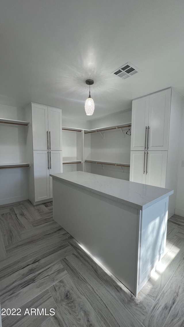 kitchen with light stone counters, white cabinets, and pendant lighting