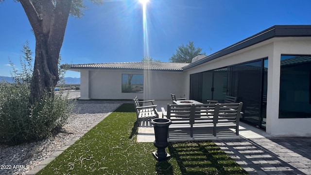 rear view of property with a sunroom, a patio area, and a yard