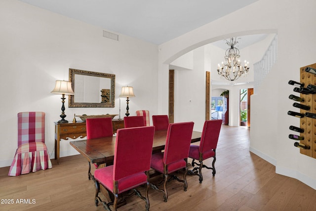 13914 E Laurel Ln, Scottsdale, AZ 85259 - dining room with arched walkways, wood finished floors, visible vents, and an inviting chandelier
