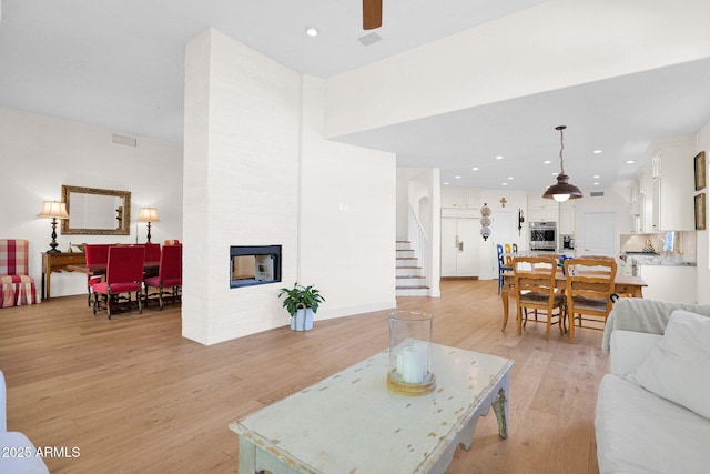 13914 E Laurel Ln, Scottsdale, AZ 85259 - living room with light wood-style flooring, recessed lighting, ceiling fan, a multi sided fireplace, and stairway