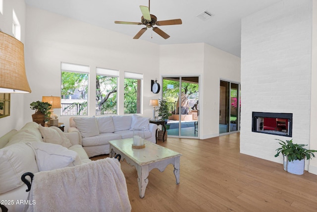 13914 E Laurel Ln, Scottsdale, AZ 85259 - living area with a ceiling fan, a stone fireplace, light wood-type flooring, a towering ceiling, and visible vents