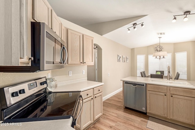 kitchen with visible vents, track lighting, a sink, vaulted ceiling, and stainless steel appliances