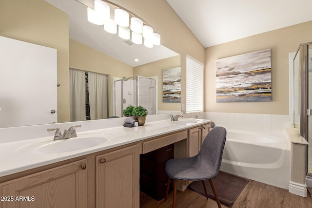 bathroom with vaulted ceiling, a sink, a garden tub, and wood finished floors