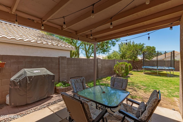 view of patio with a fenced backyard, a trampoline, grilling area, and outdoor dining space