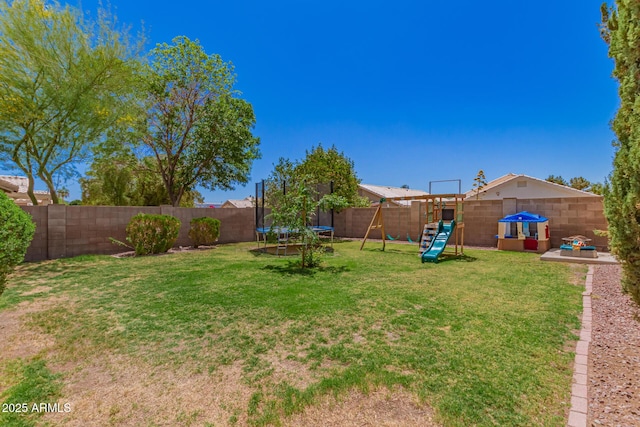 view of yard featuring a playground, a trampoline, and a fenced backyard
