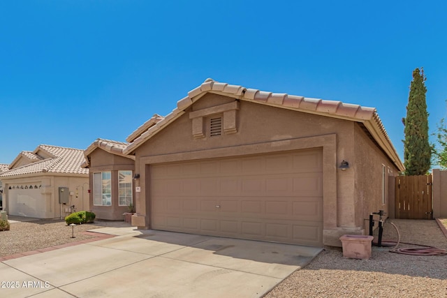 view of front of property with a tiled roof, a garage, fence, concrete driveway, and stucco siding
