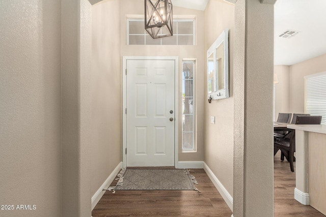foyer with baseboards, a textured wall, wood finished floors, and visible vents