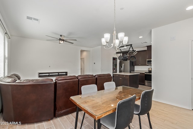 dining room with ceiling fan with notable chandelier and light hardwood / wood-style flooring