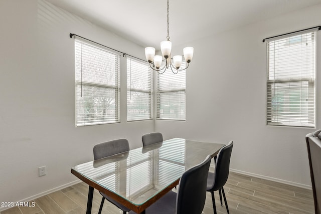 dining space with light hardwood / wood-style flooring, plenty of natural light, and a chandelier