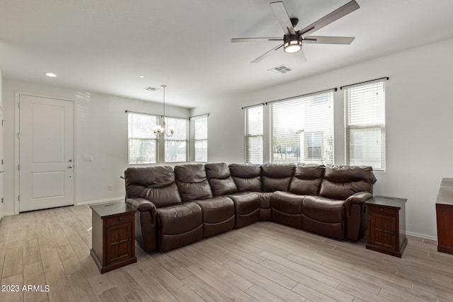 living room with light wood-type flooring and ceiling fan with notable chandelier