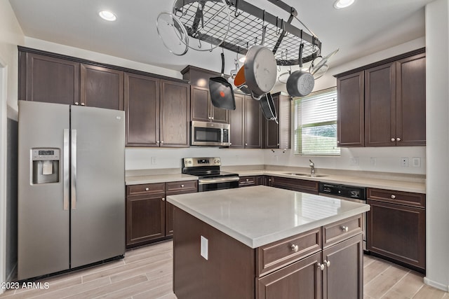 kitchen with dark brown cabinetry, sink, a kitchen island, appliances with stainless steel finishes, and light hardwood / wood-style floors