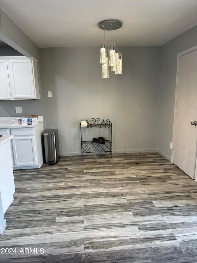 unfurnished dining area featuring light wood-type flooring and an inviting chandelier