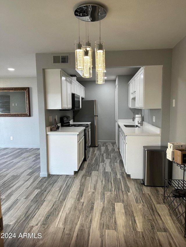 kitchen with appliances with stainless steel finishes, white cabinetry, dark hardwood / wood-style floors, and sink