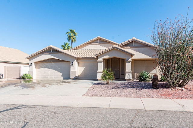 view of front of home featuring an attached garage, a tiled roof, driveway, and stucco siding