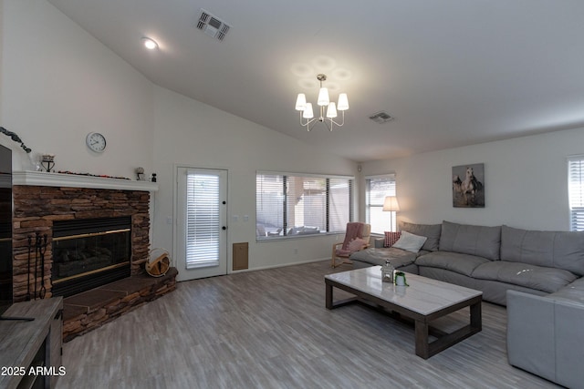 living area with wood finished floors, a notable chandelier, vaulted ceiling, and visible vents