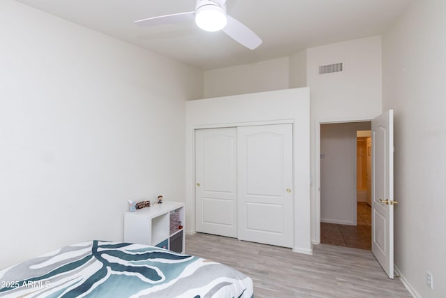bedroom featuring ceiling fan, light wood-style flooring, a closet, visible vents, and baseboards