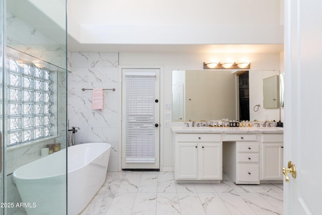 bathroom featuring a freestanding bath, a sink, tile walls, double vanity, and marble finish floor