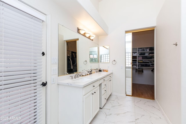 full bath with a sink, a spacious closet, double vanity, and marble finish floor