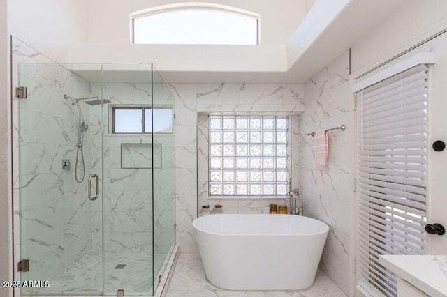 bathroom featuring a marble finish shower, a wealth of natural light, a freestanding bath, and marble finish floor
