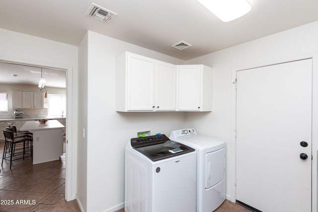 laundry room with washer and dryer, light tile patterned floors, visible vents, and cabinet space