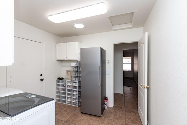 kitchen with tile patterned floors, freestanding refrigerator, white cabinetry, and washer and clothes dryer